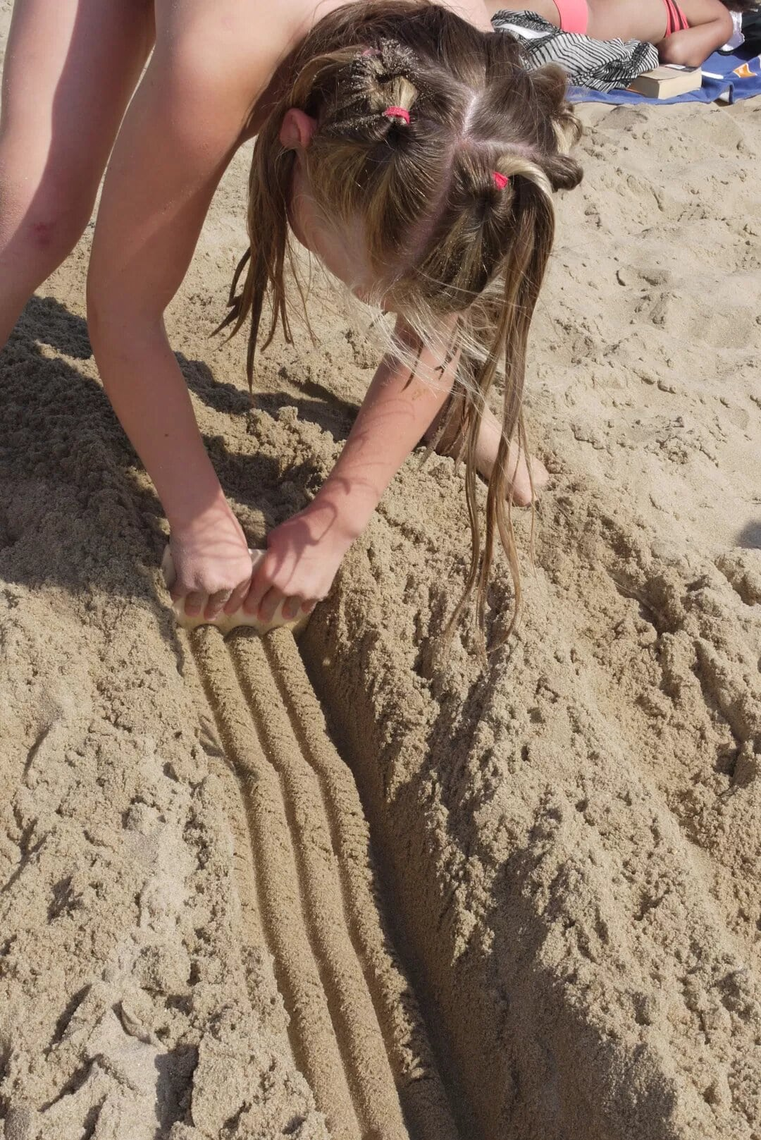 Meisje speelt met een zandkam op het strand. Zandkammen zijn ideaal om mee te nemen en staat garant voor eindeloos speelplezier! 